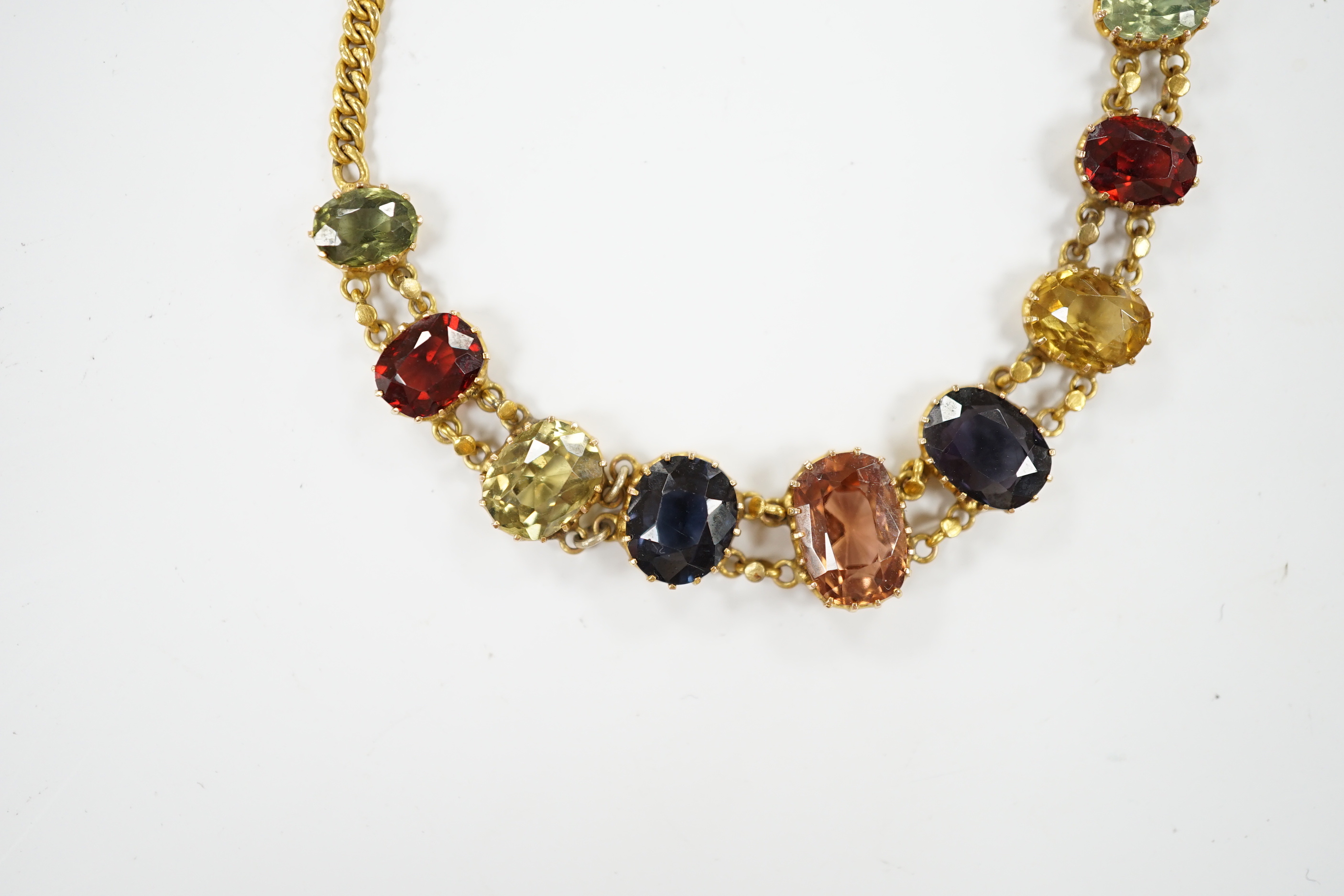 An early 20th century yellow metal and graduated multi-coloured oval cut zircon? set bracelet, 15.5cm, gross weight 7 grams.